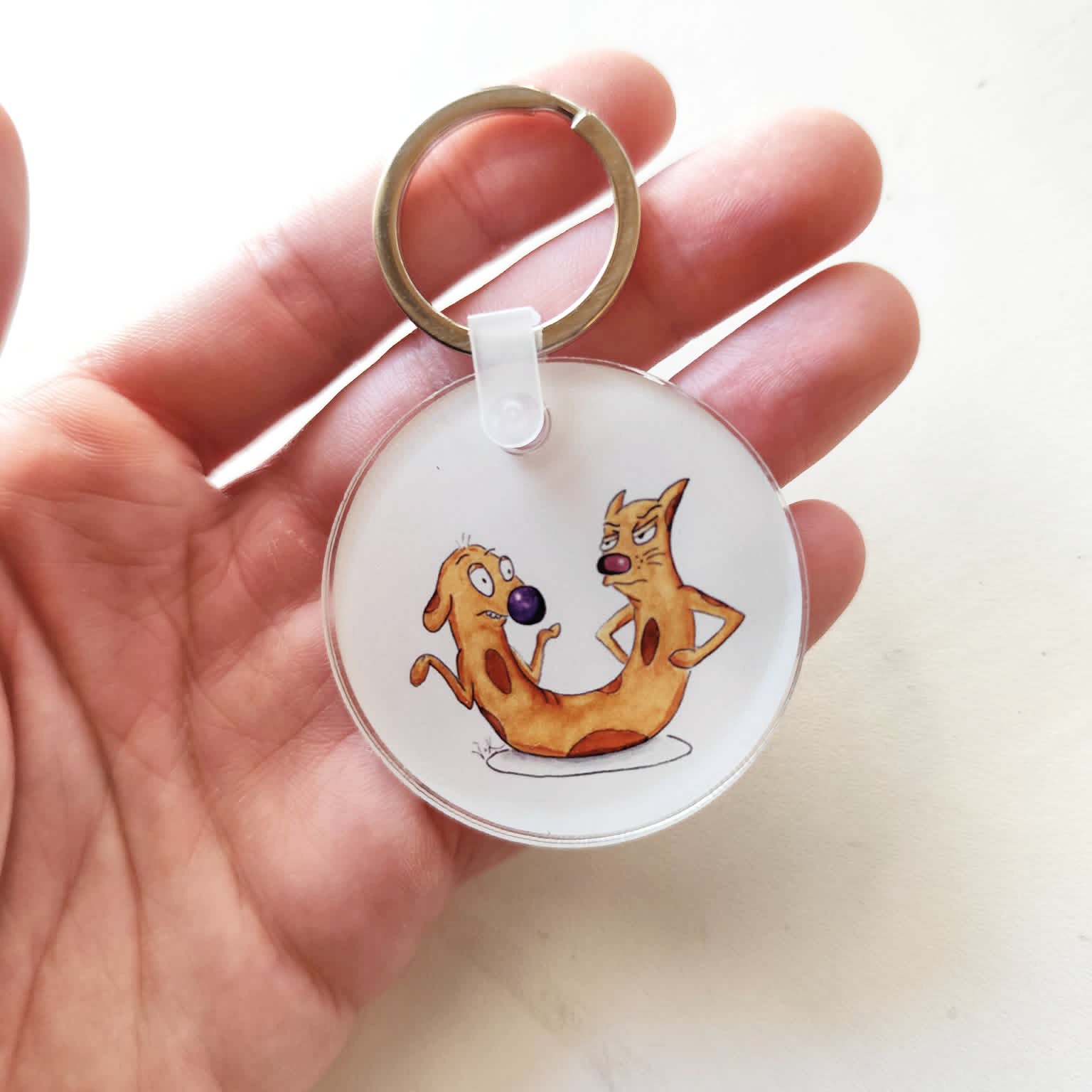 Cat-ch Me If You Can acrylic keychain held in hand for size reference.