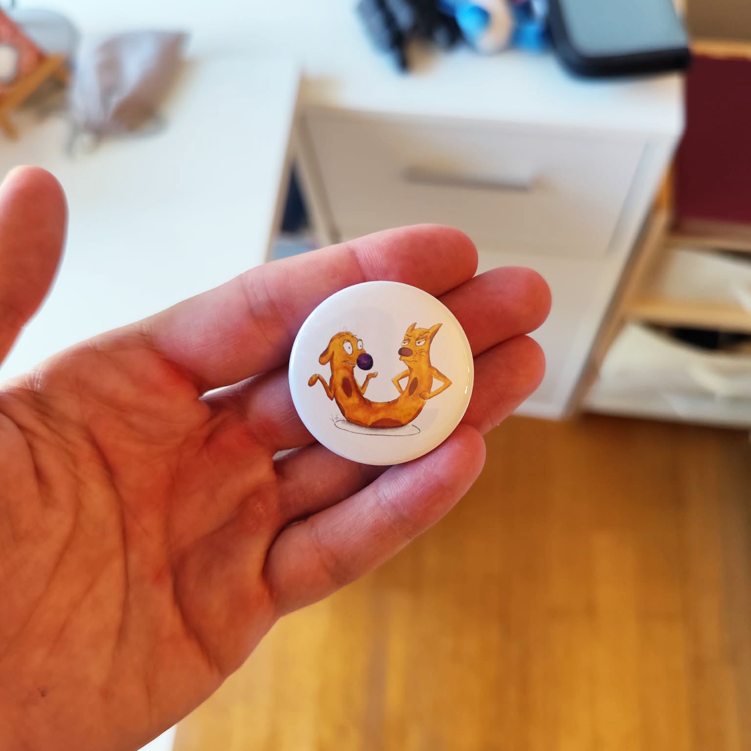 Cat-me If You Can illustrated pin button held in hand for size reference.