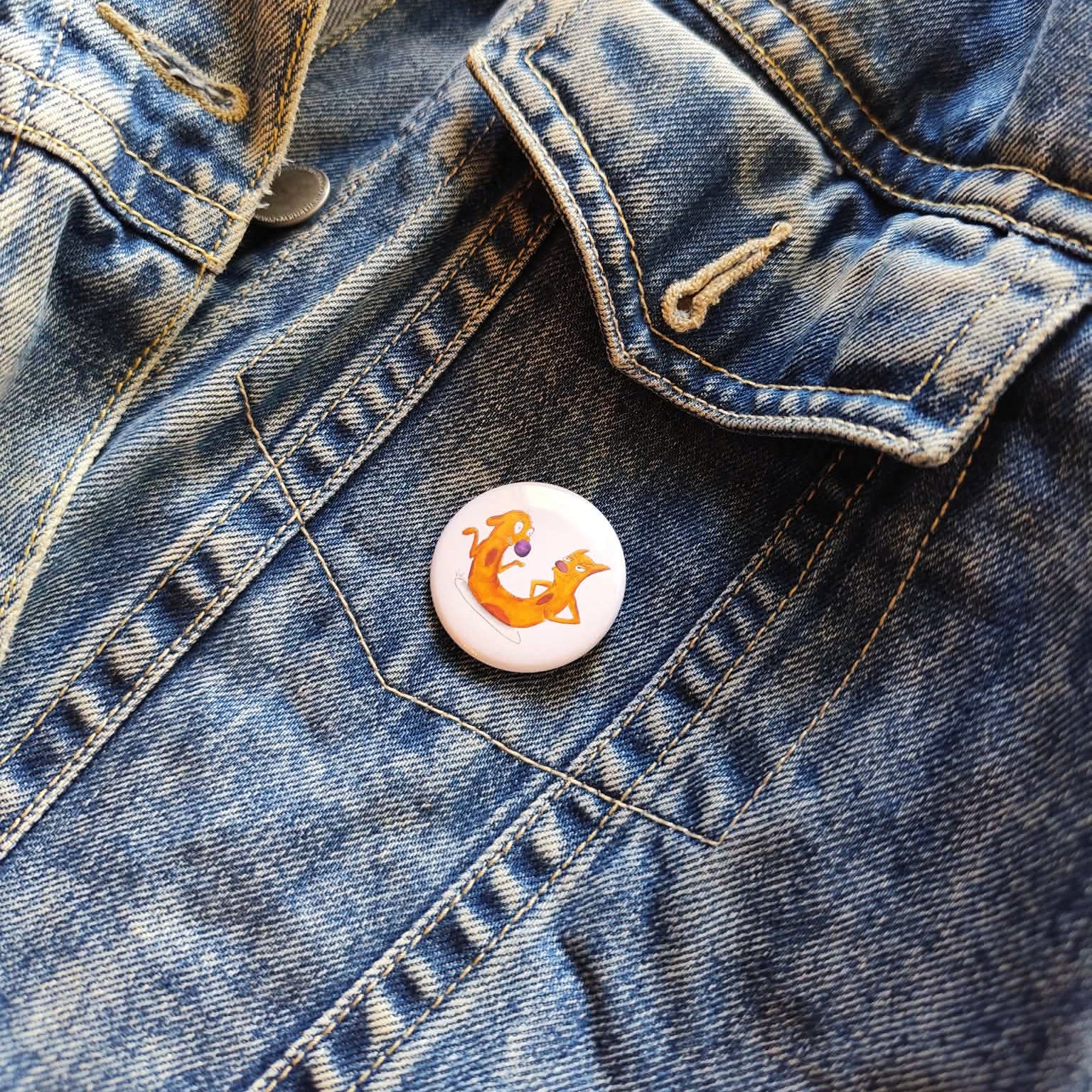 Cat-me If You Can illustrated pin button attached to a denim jacket.