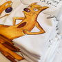 Stack of folded white cotton T-shirts featuring the hand-drawn "Exhausted Spy" illustration.
