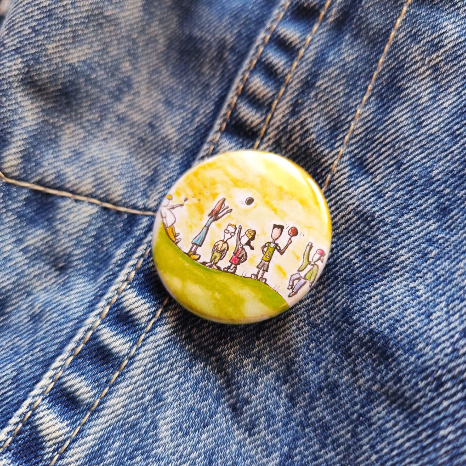 Childhood Days illustrated pin button attached to a denim jacket.