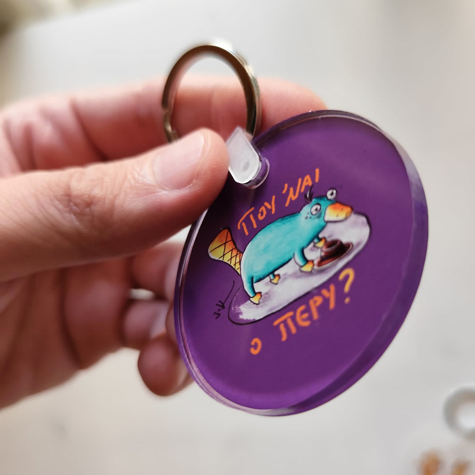Exhausted Spy acrylic keychain held in hand for size reference.