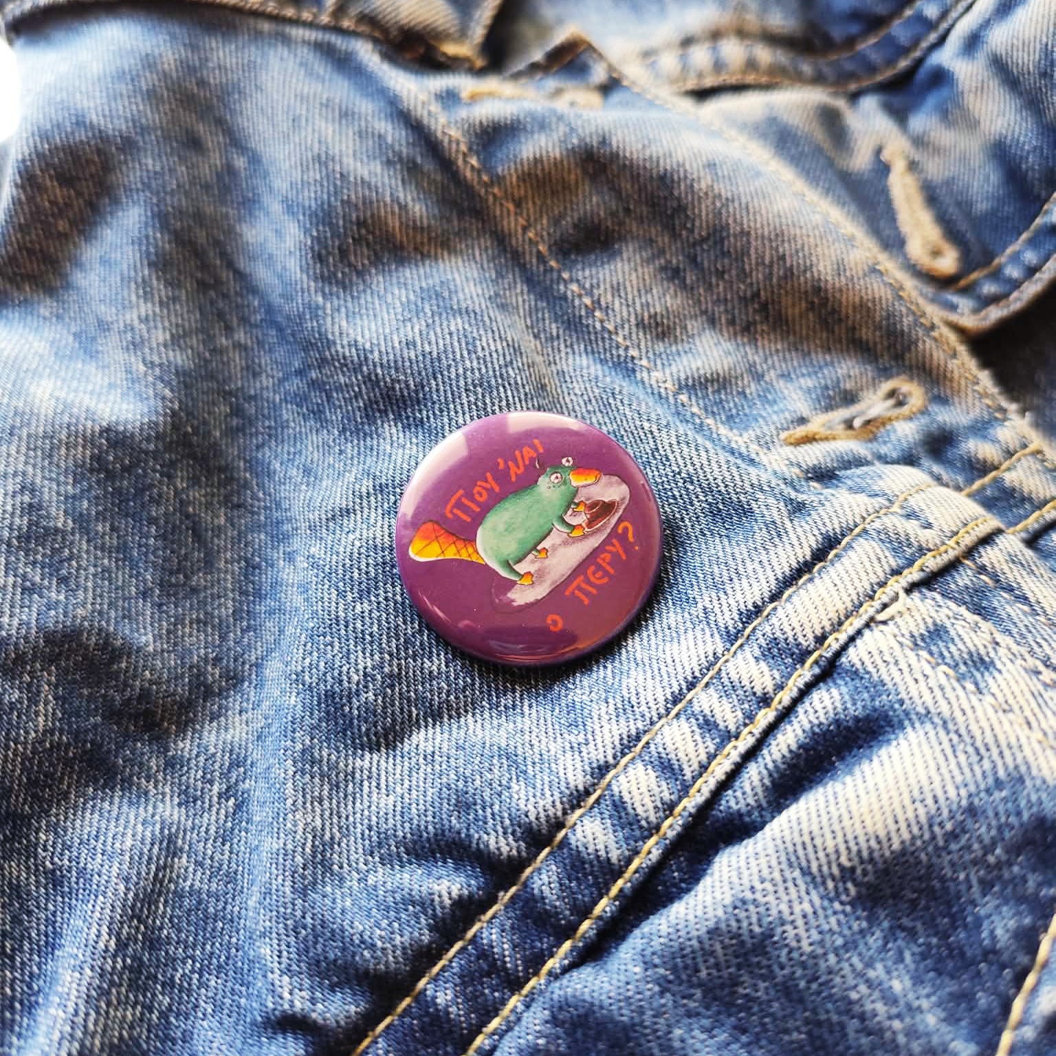 Exhausted Spy illustrated pin button attached to a denim jacket.