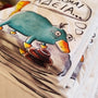 Stack of folded white cotton T-shirts featuring the hand-drawn "Exhausted Spy" illustration.