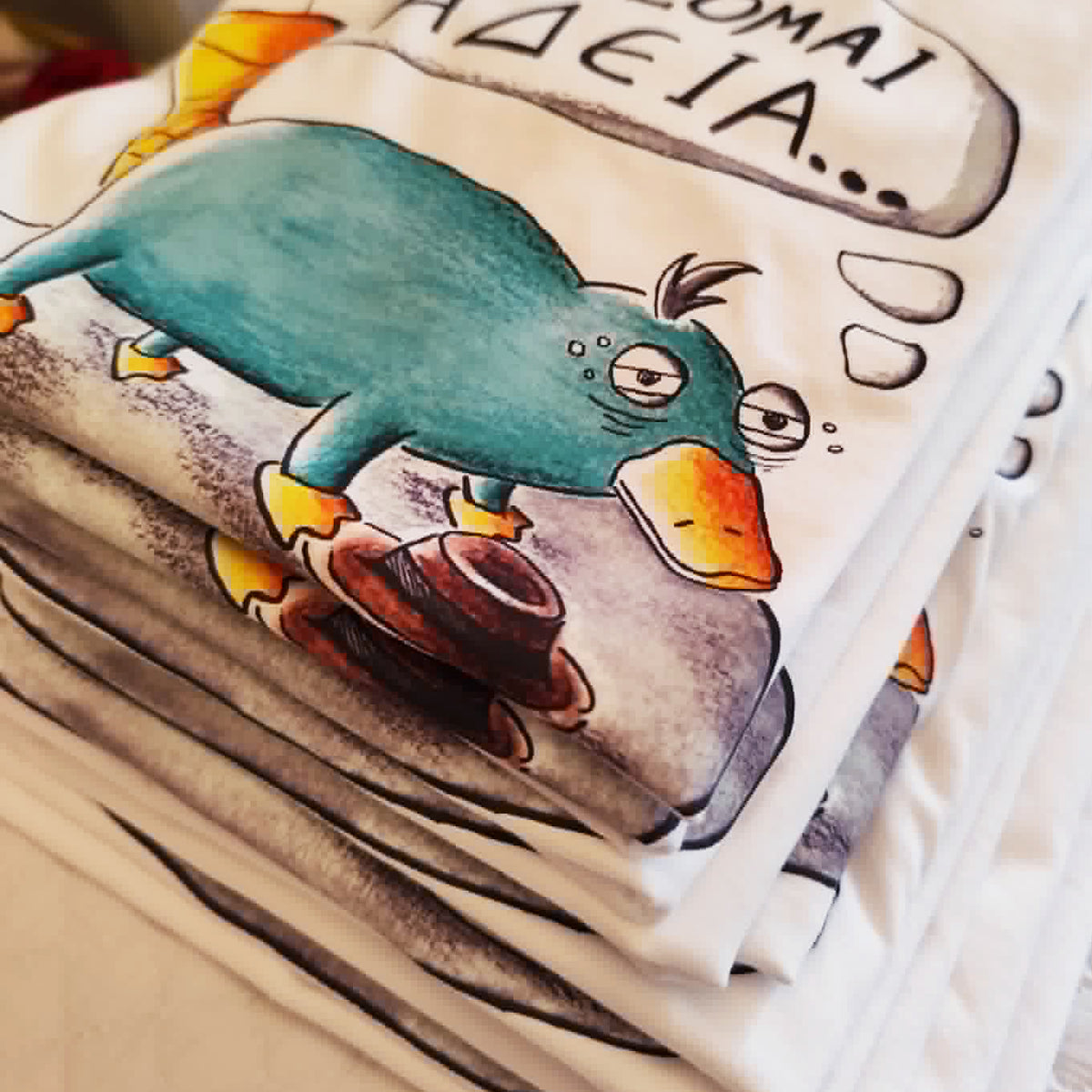 Stack of folded white cotton T-shirts featuring the hand-drawn "Exhausted Spy" illustration.