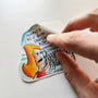 Hand applying Ikarian Dance illustrated vinyl sticker.