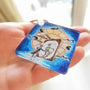 Never Grow Up acrylic keychain held in hand for size reference.