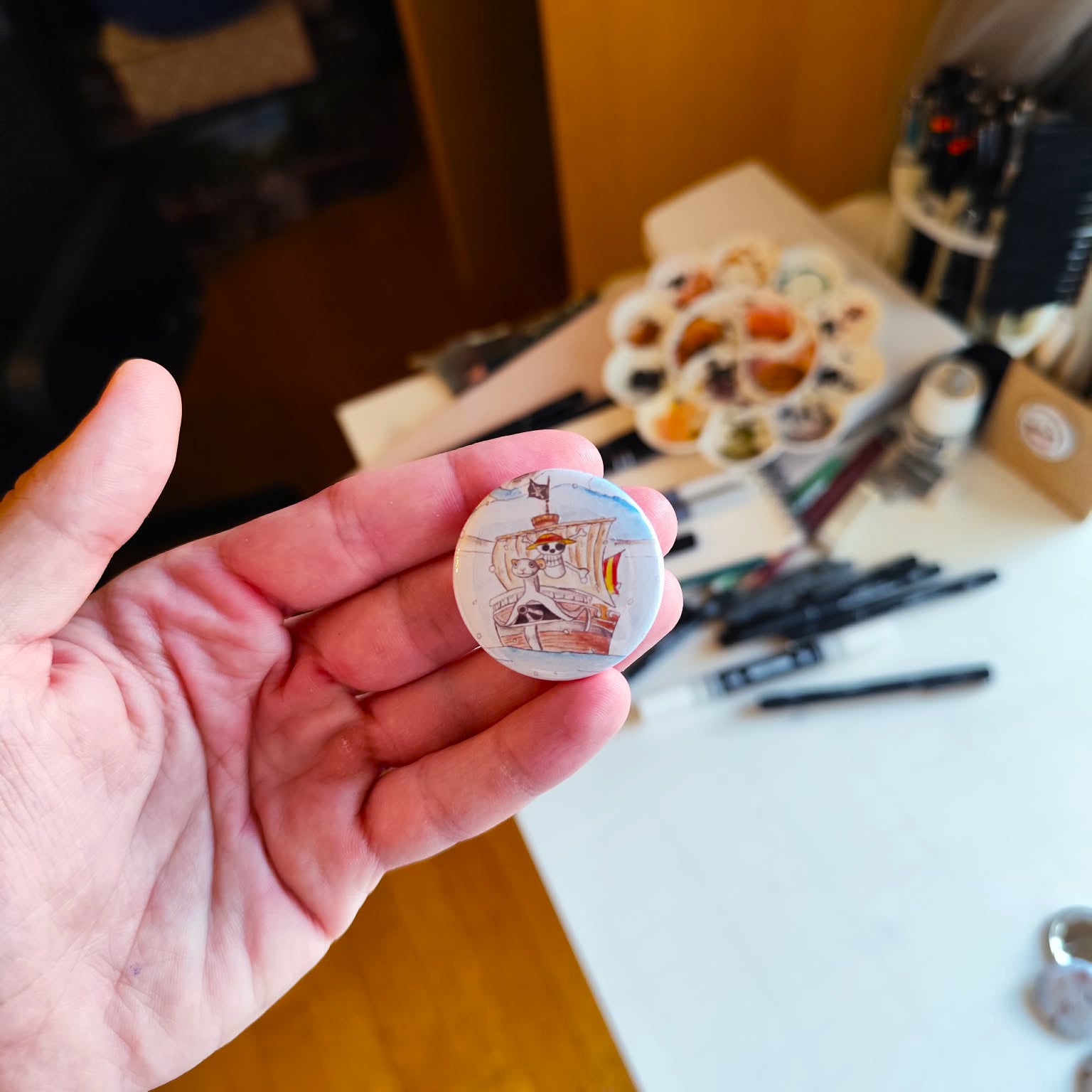 One Ship illustrated pin button held in hand for size reference.