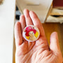 Reindeer Companion illustrated pin button held in hand for size reference.