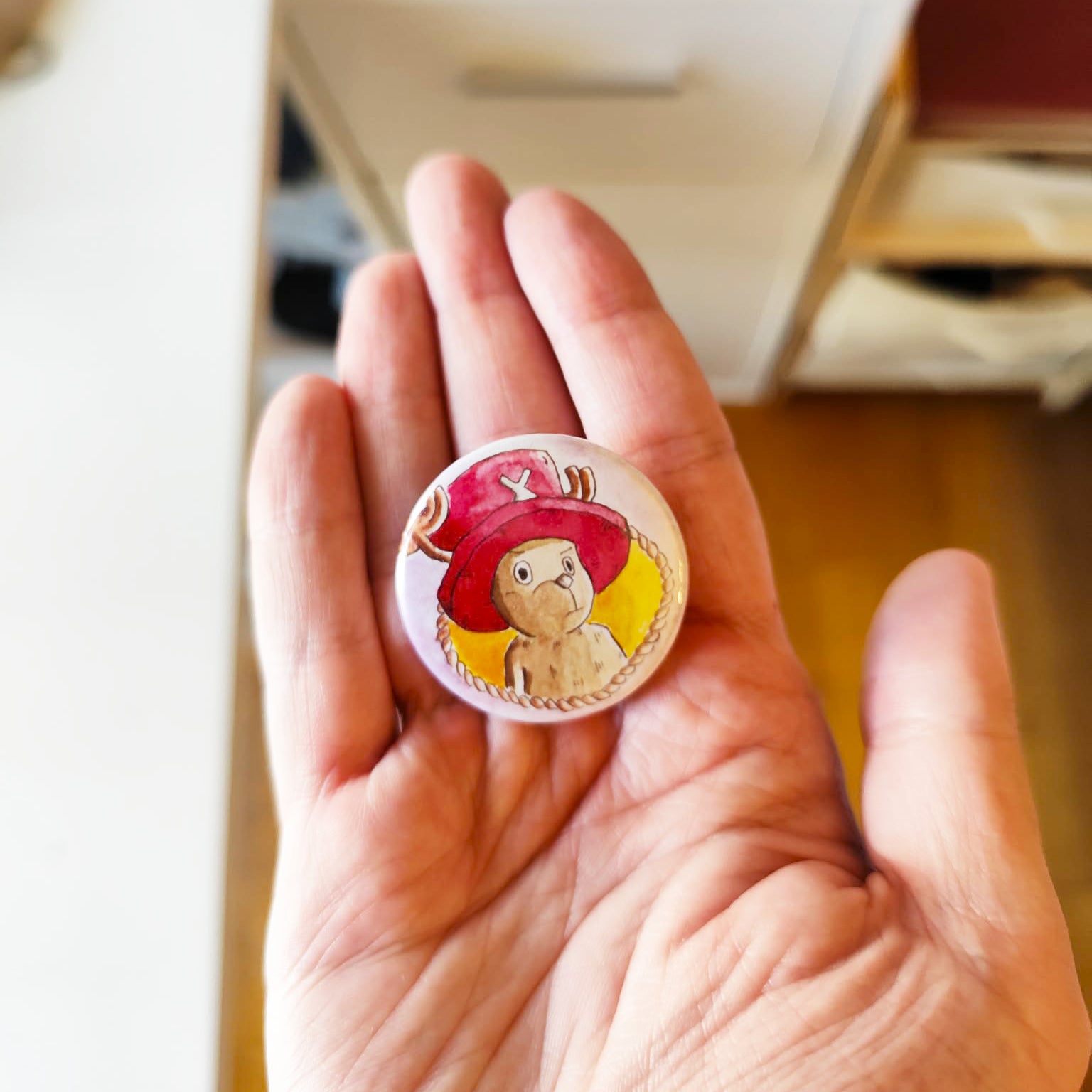 Reindeer Companion illustrated pin button held in hand for size reference.